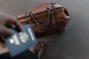 Hombre con un pasaporte en la mano y un maletÃ­n el el piso