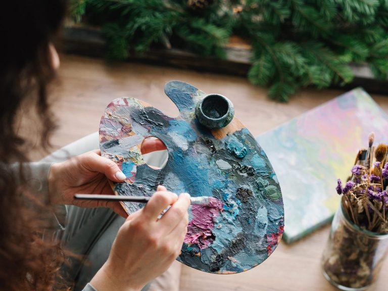 Mujer pintando con un pincel y paleta de colores de madera