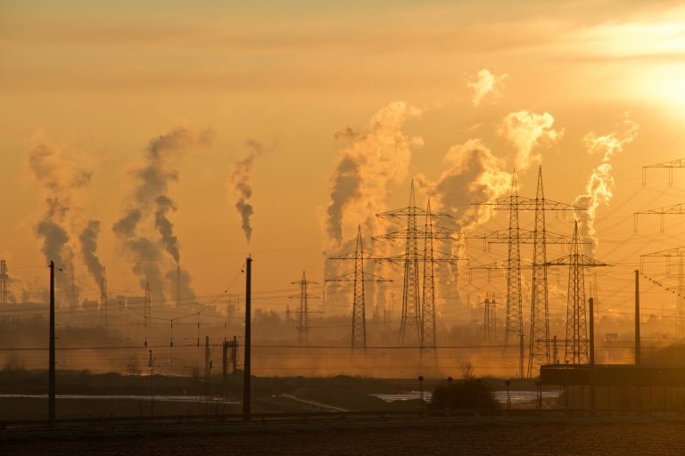 Torres elÃ©ctricas de alta tensiÃ³n con fabricas al fondo desechando gases tÃ³xicos